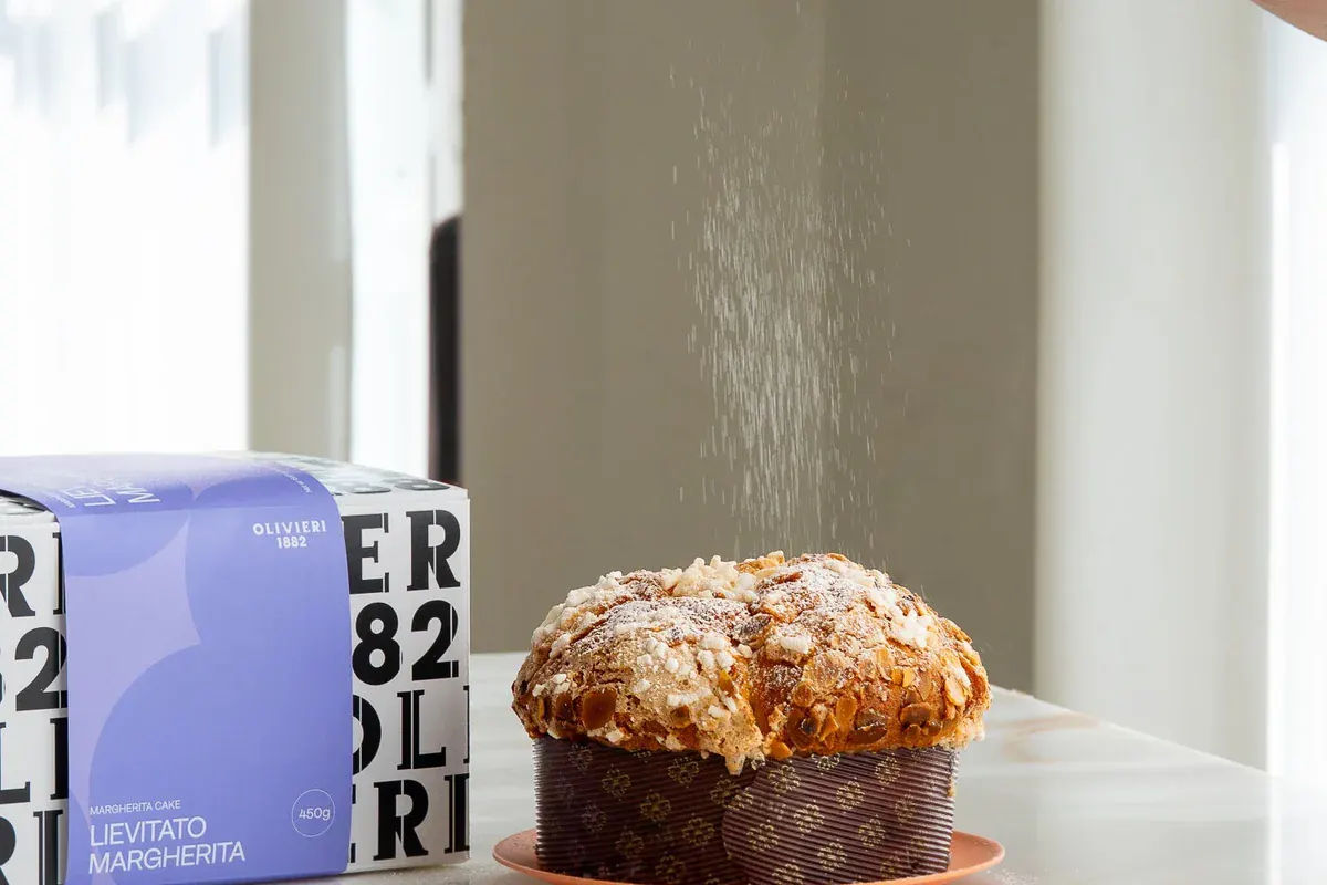 Panettone Olivieri 1882 spolverato di zucchero a velo accanto alla confezione Margherita